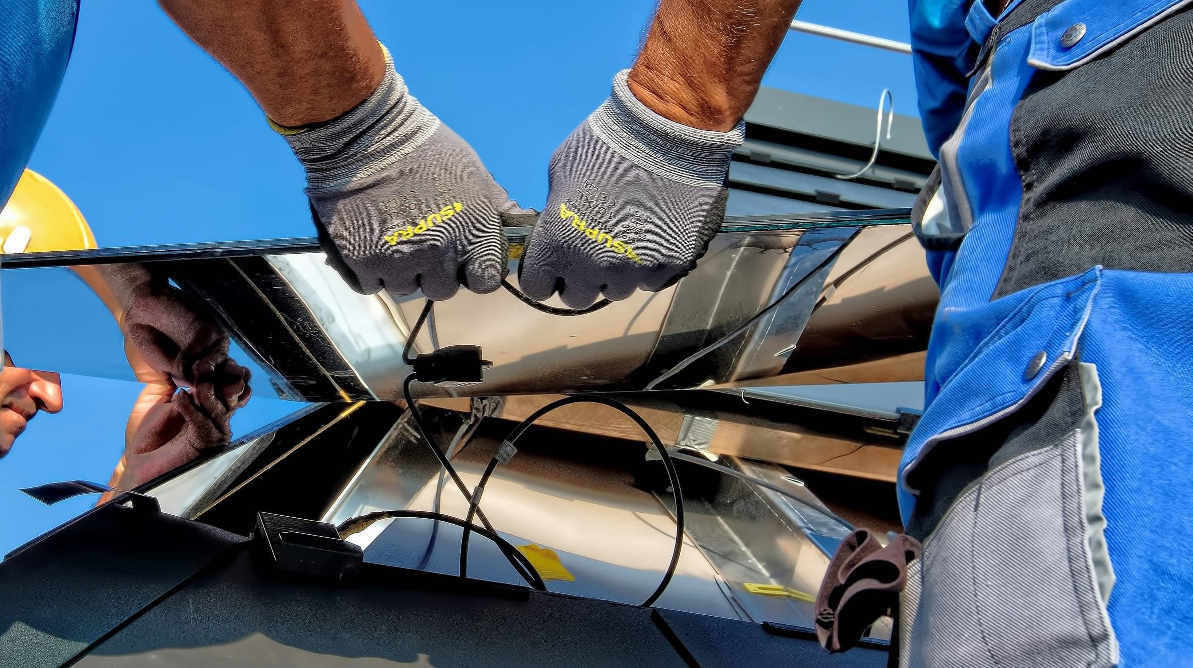 Two installers fitting a solar panel onto a roof mount